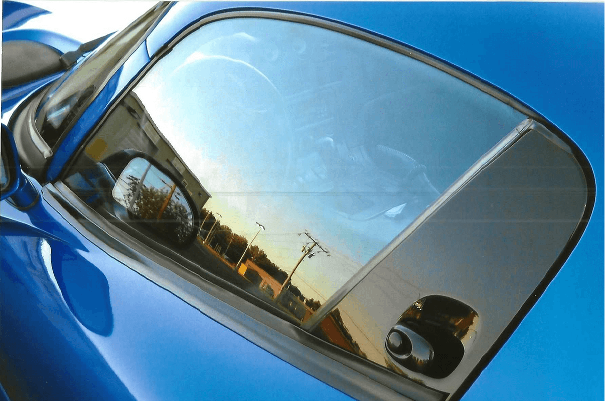 Blue car window reflecting sunset scenery
