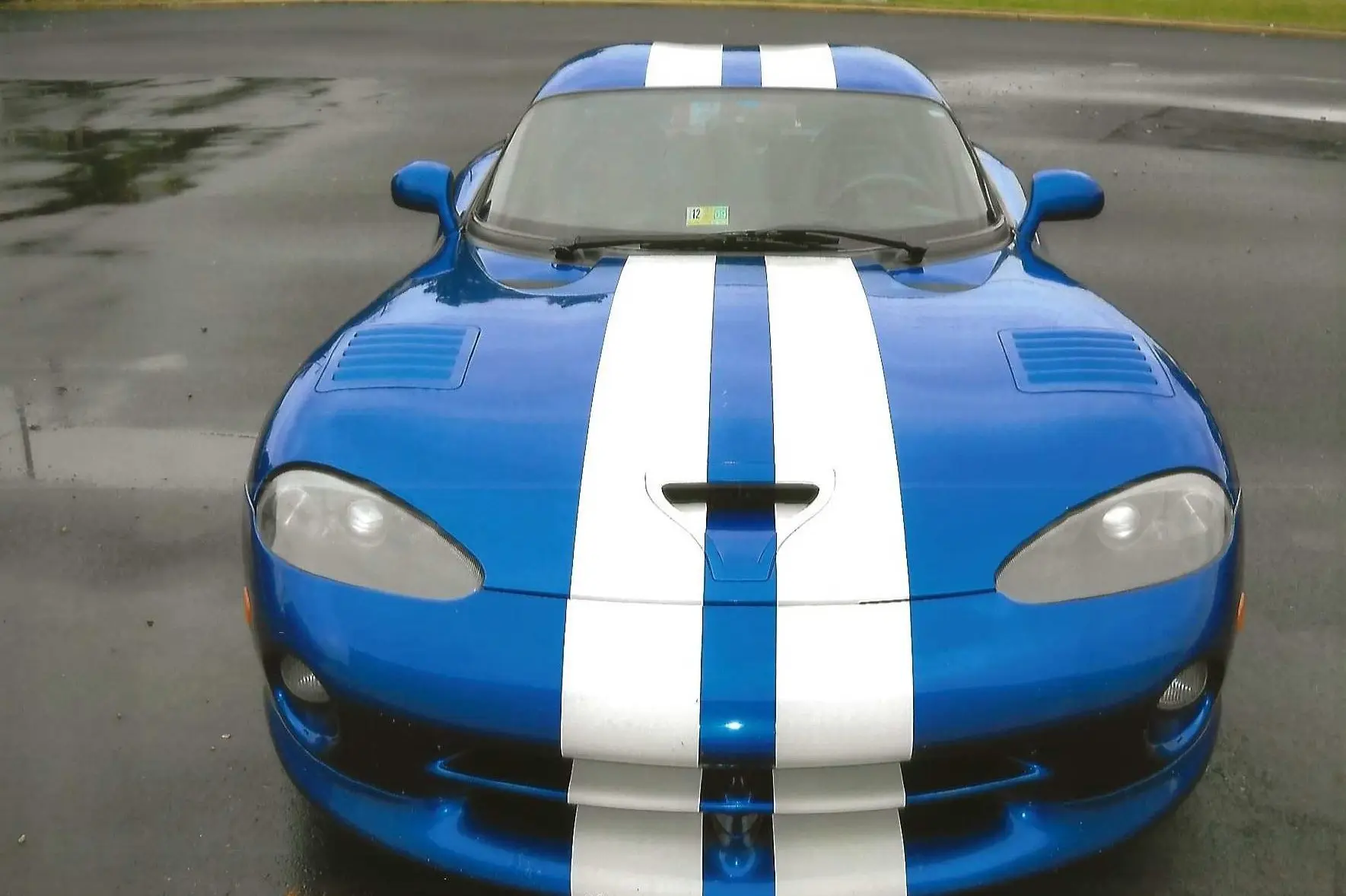 Blue sports car with white racing stripes on the hood.