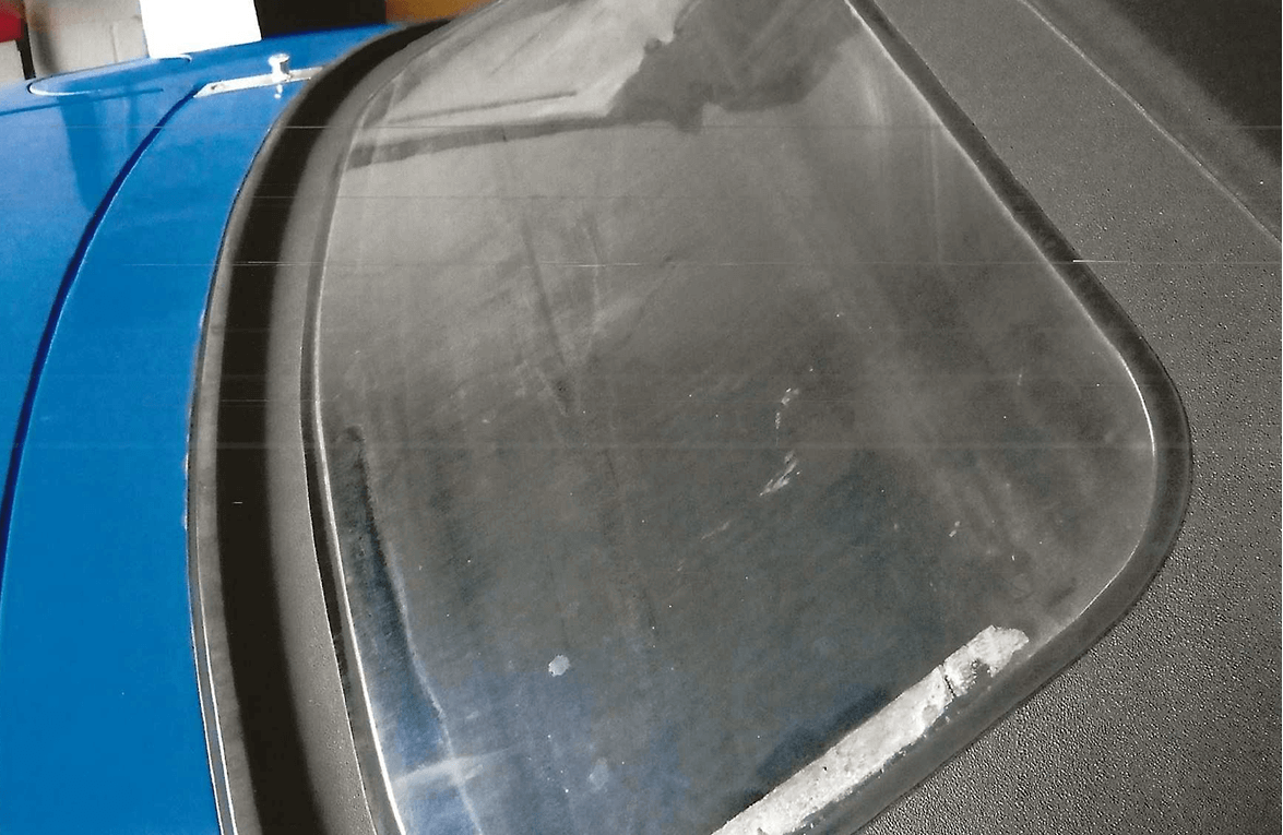 Close-up of a weathered car windshield with visible dirt and smudges.