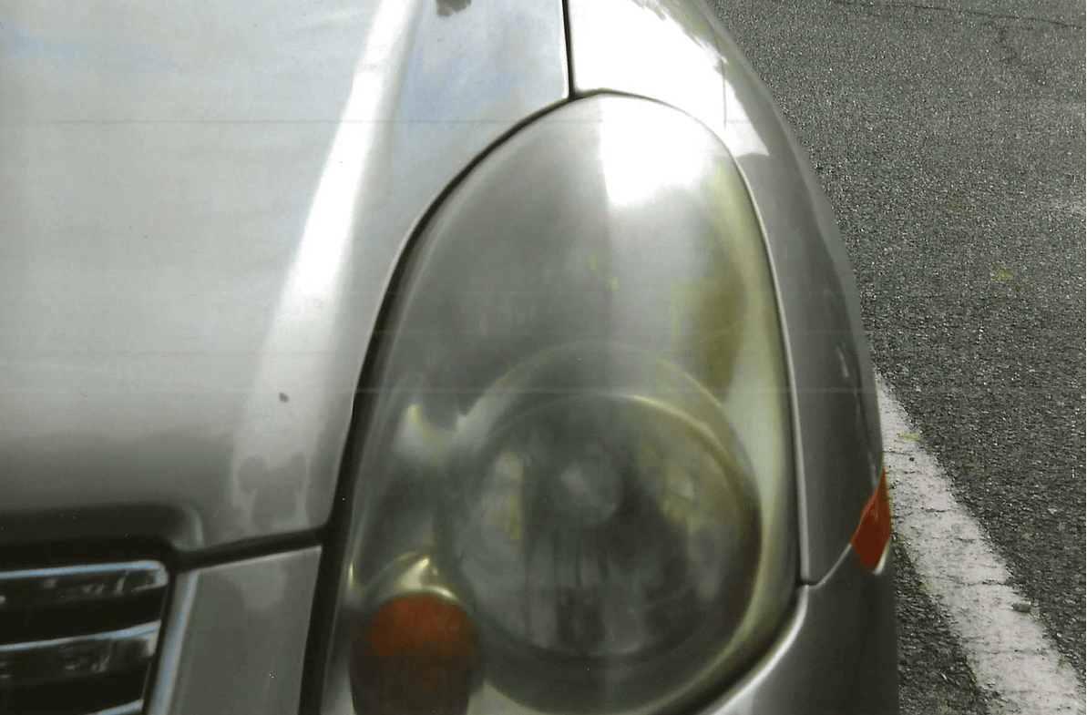Close-up of a foggy car headlight on a silver vehicle.