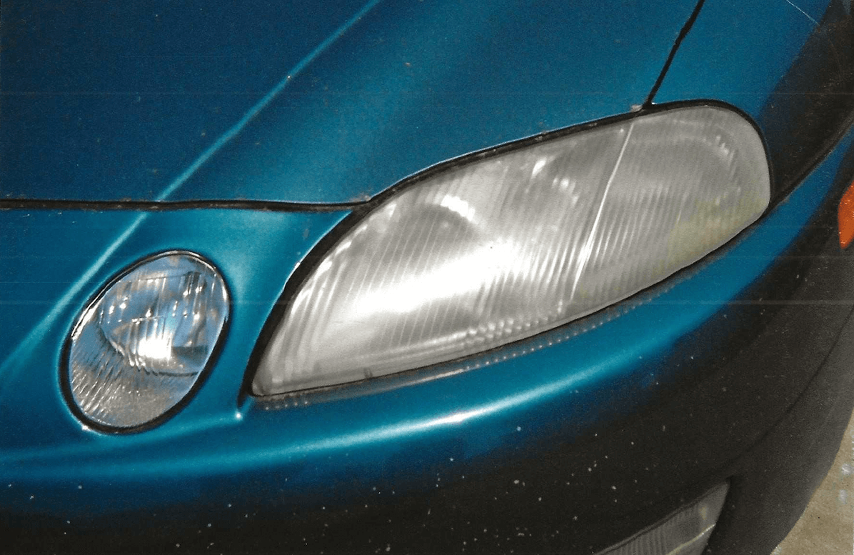 Close-up of a blue car's headlight with visible wear.
