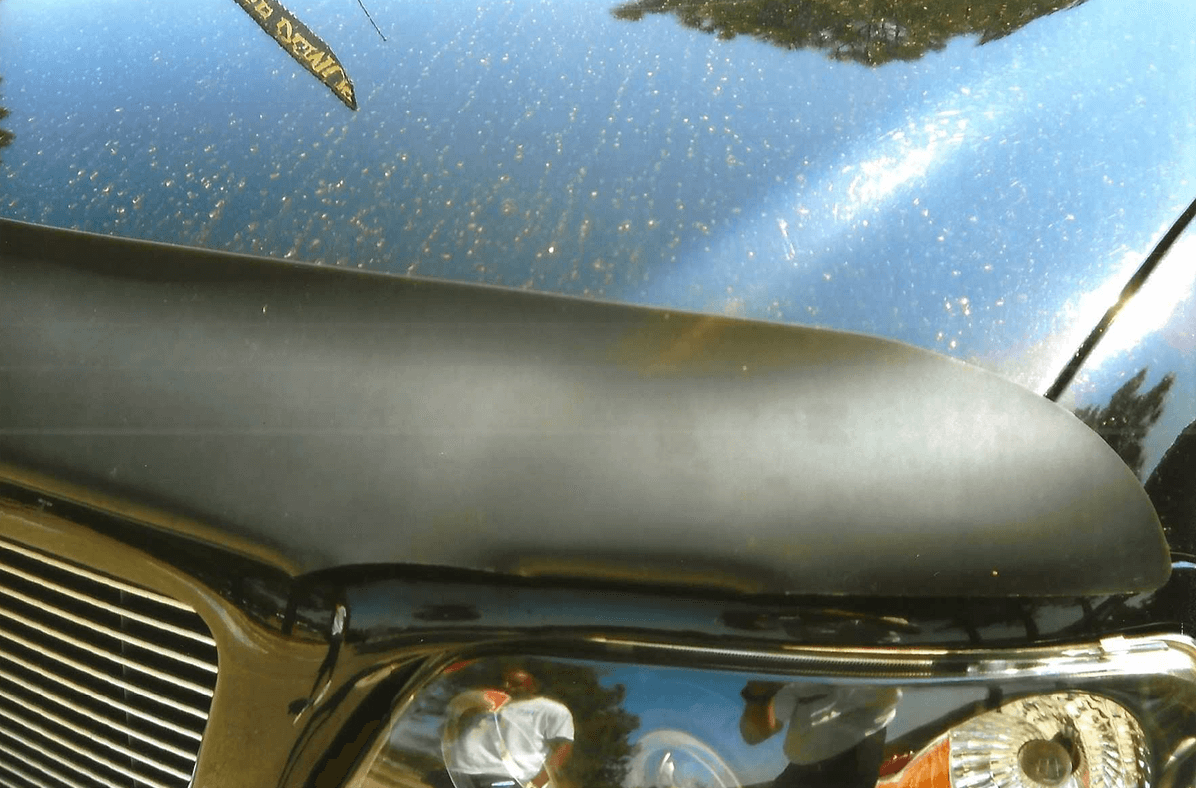 Close-up of a shiny motorcycle fuel tank and seat under sunlight.