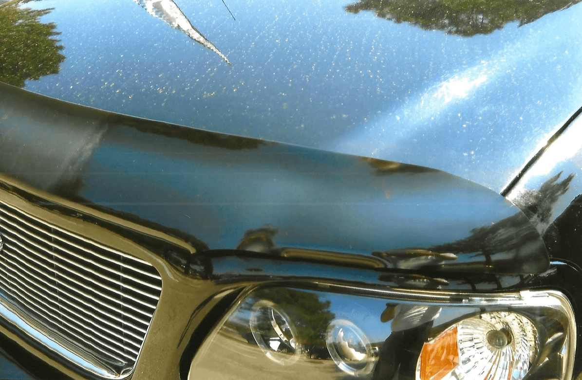 Close-up of a car's headlight and front grille under sunlight.