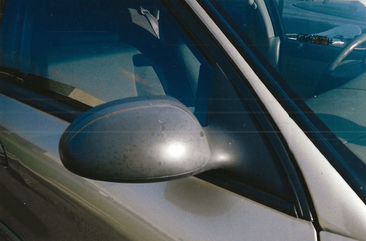Close-up of a car's side mirror with the window partially open.